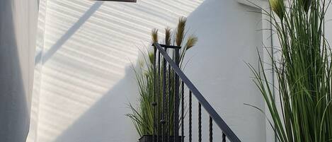 A staircase with a metal railing, a potted plant, and a sign that reads "Home, is the best place".