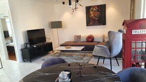 A modern living room with a sofa, a coffee table, a TV, and a red telephone booth. - IN Fresh - Holiday House IN Šibenik Near Center AND Beach With Parking (Šibenik)