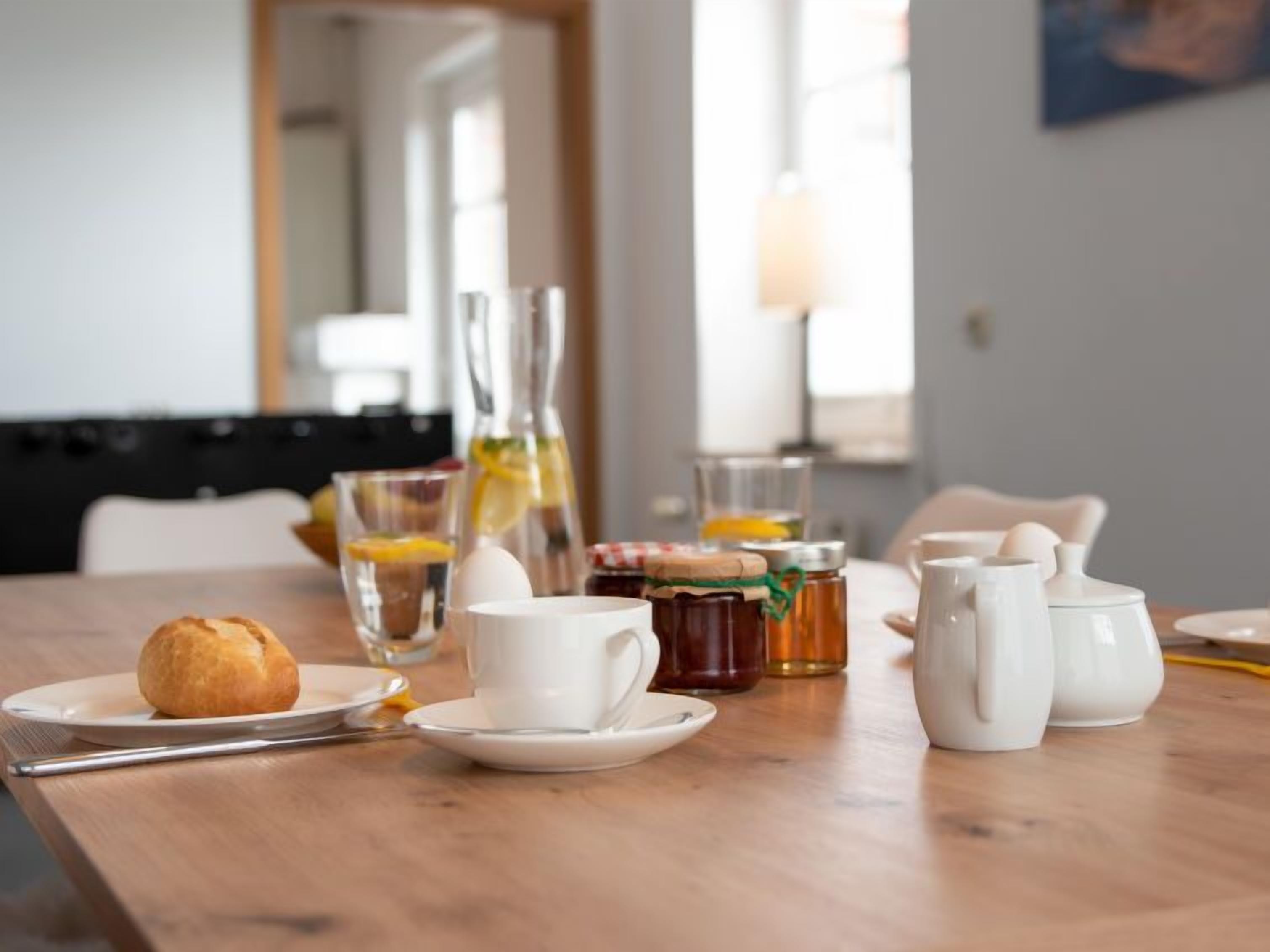 Una tavola per la colazione con un croissant, tazze di caffè, un bicchiere di succo d'arancia e barattoli di miele.