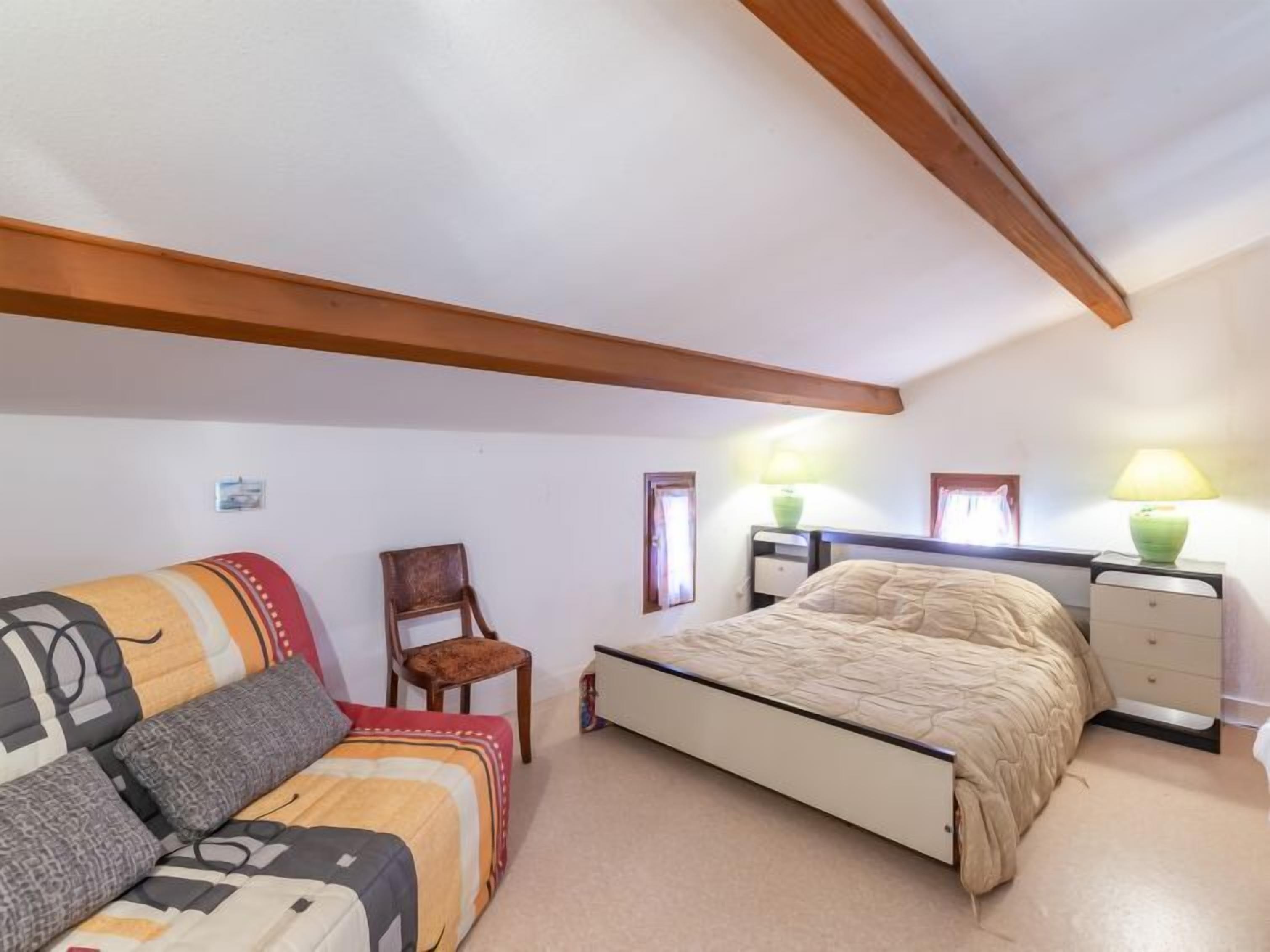 Une chambre à coucher avec un lit, une chaise, une table de chevet et deux lampes.