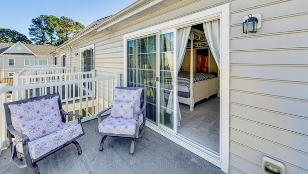 A covered outdoor area with two rocking chairs, a white railing, and a sliding glass door leading to a bedroom. - 2 Mi to Beach: Townhome w/ Breezy Balcony! (Rehoboth Beach)