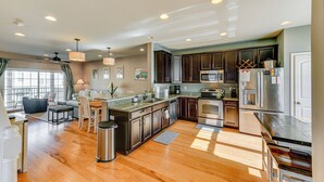 A spacious kitchen with wooden flooring, dark cabinets, stainless steel appliances, and a dining area with a sofa and table. - 2 Mi to Beach: Townhome w/ Breezy Balcony! (Rehoboth Beach)