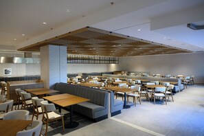A spacious restaurant with high ceilings, wooden beams, and a mix of booths and tables. - Poseidon Beach Resort (Golden Sands)