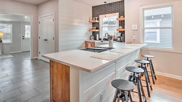 A modern kitchen with a central island, bar stools, and built-in shelves. - Charming Downtown Home w/ Updated Interior! (Oklahoma City)