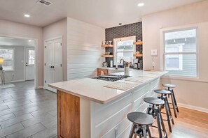 Una cocina moderna con una isla central, taburetes de bar y estanterías empotradas.