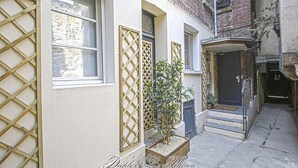 A narrow alleyway with a building featuring a wooden lattice window, a small potted plant, and a door with a sign. - Super calm cosy & cute 2 bdr at the heart of Old Honfleur- Duplex Le Pélican ★★★★ (Honfleur)