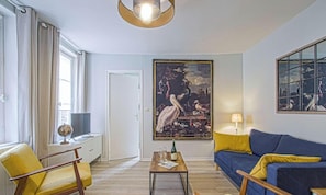 A living room with a sofa, armchairs, a coffee table, a painting, and a globe on a cabinet.