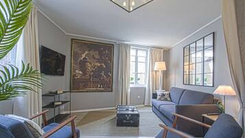 A living room with a sofa, two armchairs, a coffee table, and a painting on the wall.