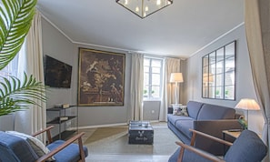 Ein Wohnzimmer mit einer Couch, zwei Sesseln, einem Couchtisch und einem Bild an der Wand.