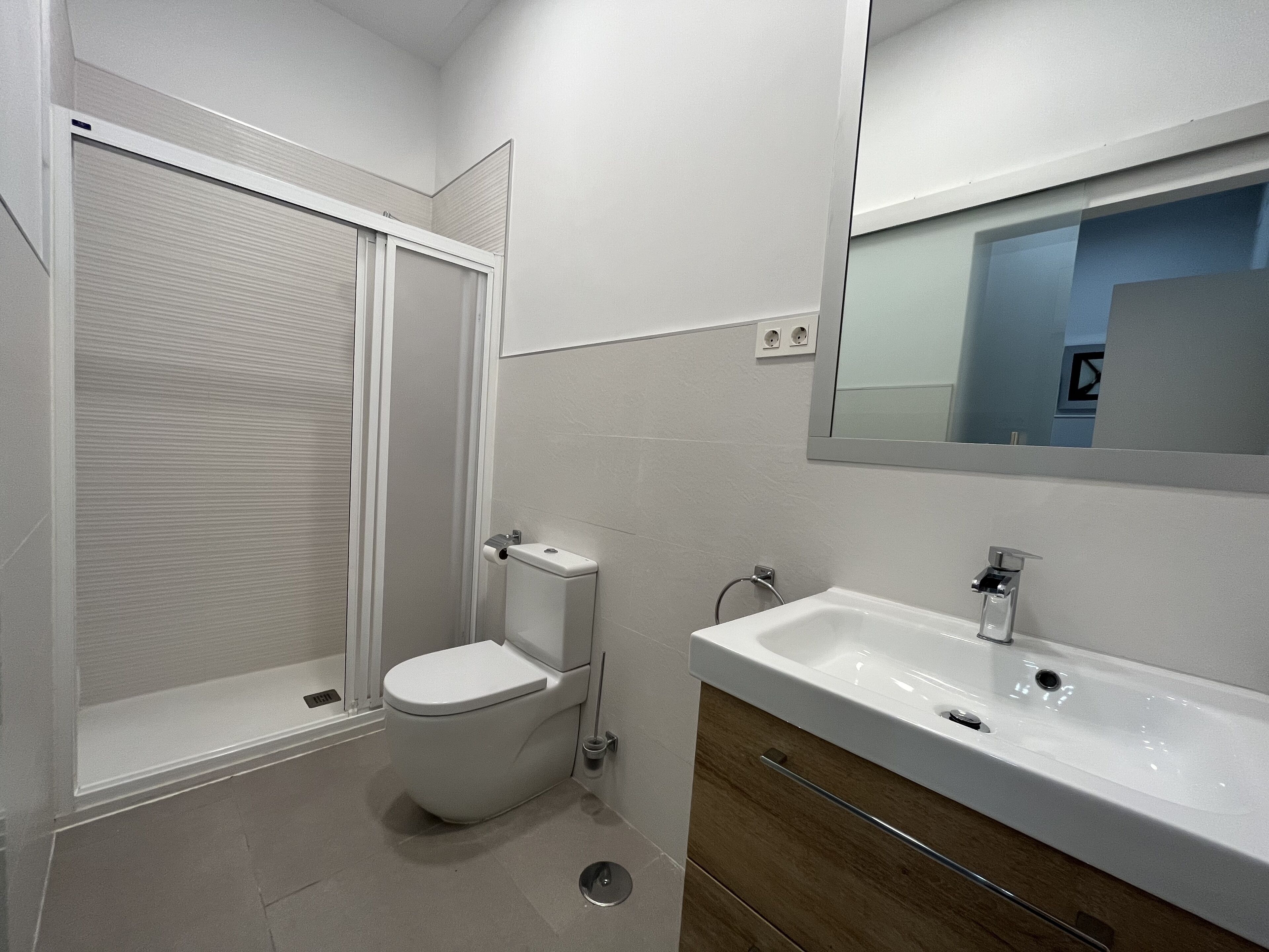 A modern bathroom with a toilet, shower, and sink.