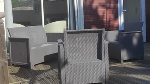 A covered outdoor patio with wicker furniture and a wooden deck. - Bungalow (BREM SUR MER)