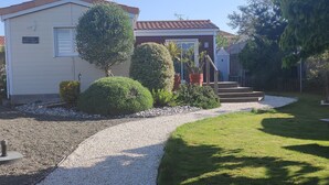 A residential property with a paved driveway, a wooden staircase, and a well-maintained lawn. - Bungalow (BREM SUR MER)