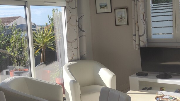 A hotel room with a bed, a desk, a chair, and a window with a view of greenery and a building. - Bungalow (BREM SUR MER)