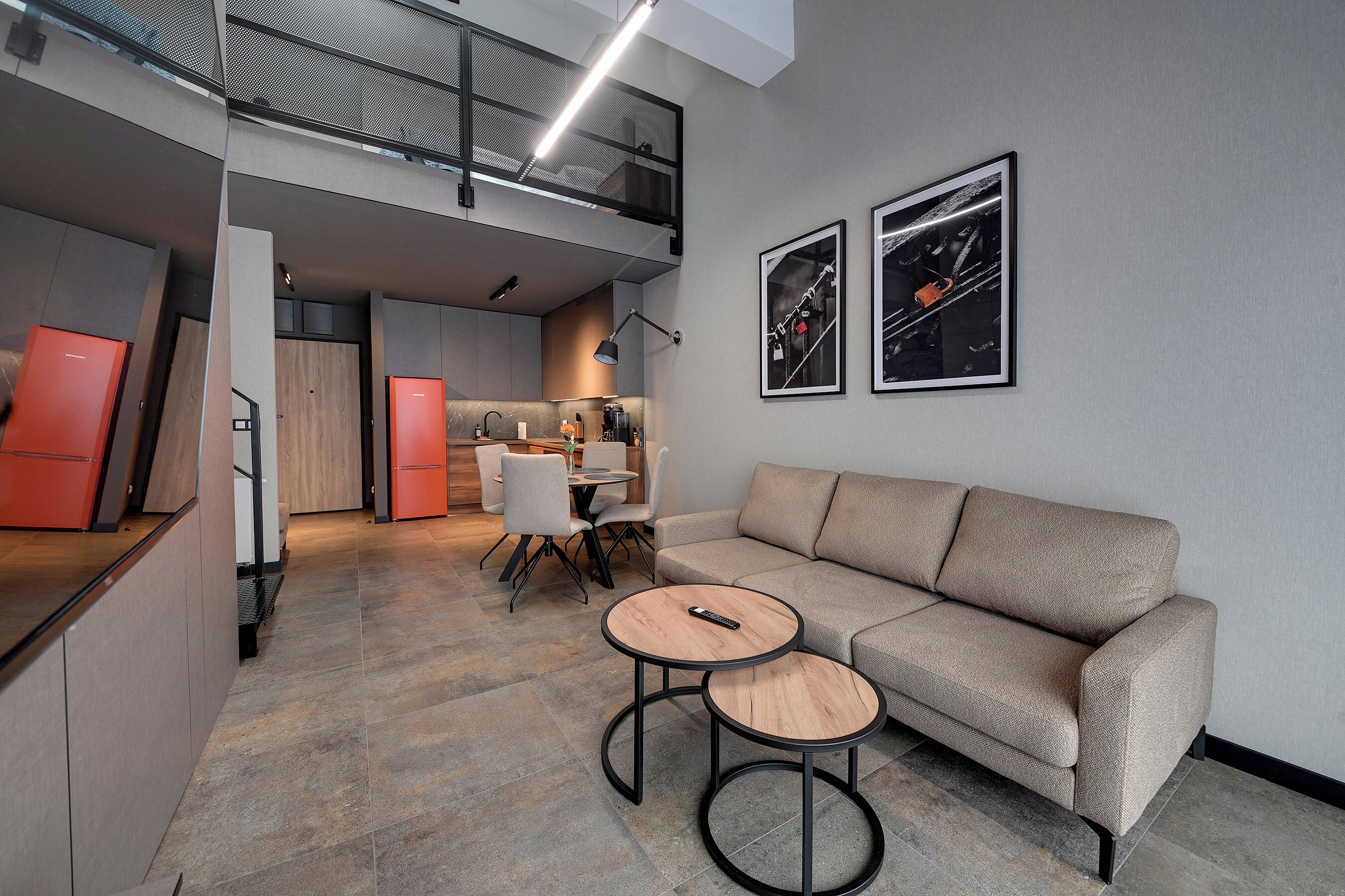Een modern interieur met een bank, twee ronde tafels, een keukenhoek en een eethoek.