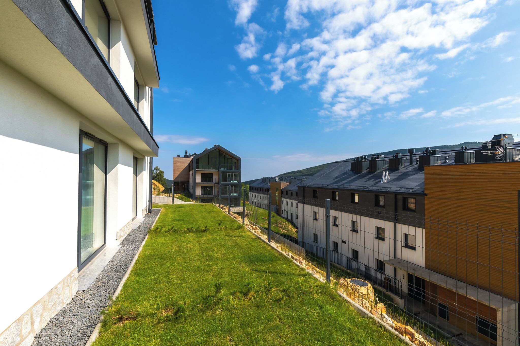A modern building with a flat roof, a grassy area, and a clear blue sky.