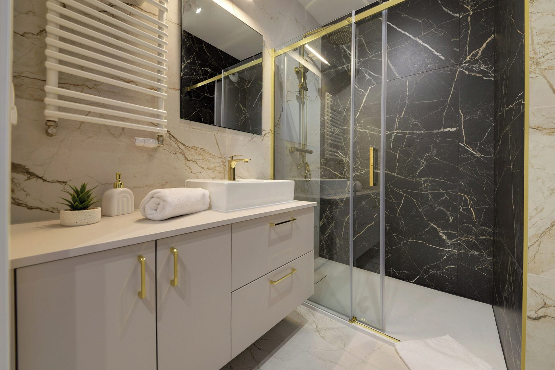 Une salle de bain moderne avec un meuble-lavabo en marbre, une cabine de douche en verre et une serviette blanche posée sur le comptoir.