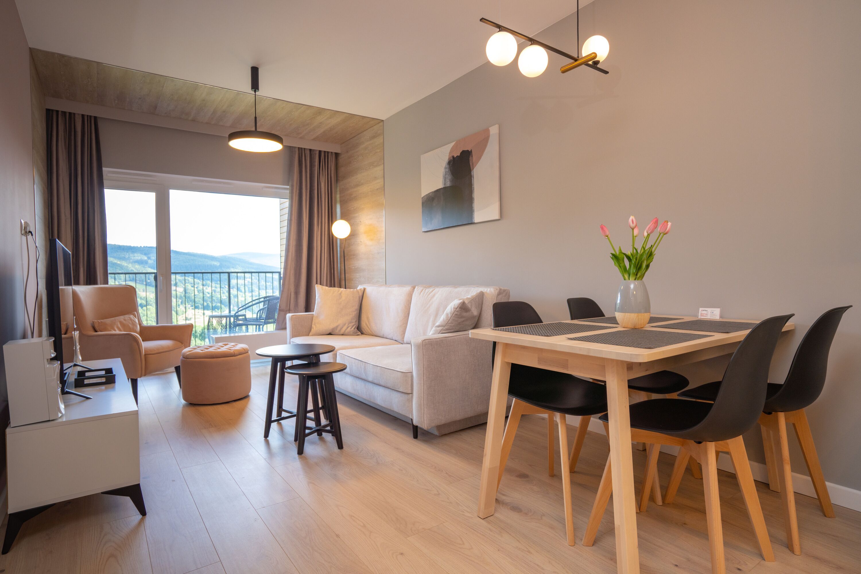 Een moderne woonkamer met een bank, een eettafel met stoelen, een salontafel en uitzicht op de natuur.