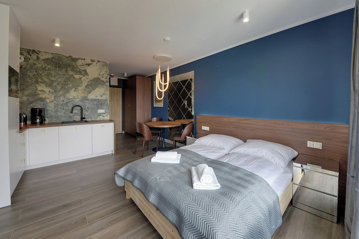 Une chambre d’hôtel moderne équipée d’un lit, d’un petit coin repas et d’une kitchenette.