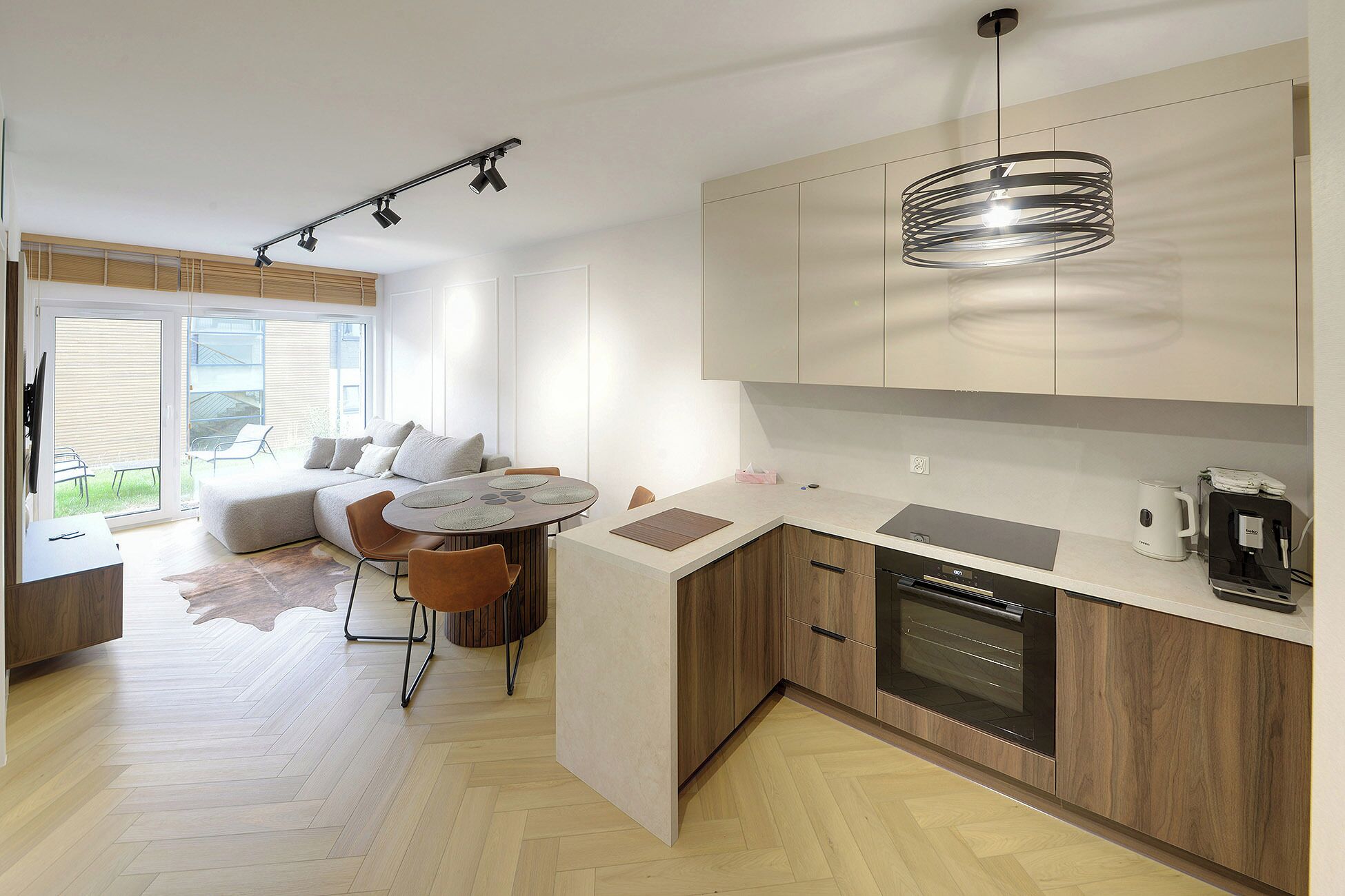 Une cuisine moderne avec des meubles en bois, un lave-vaisselle encastré et un coin repas comprenant une table ronde et des chaises.