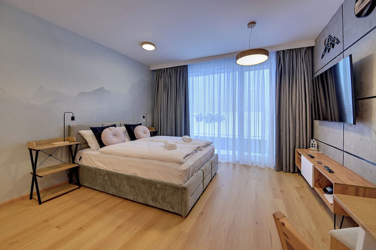 Une chambre moderne avec un lit, des tables de chevet, un bureau et un téléviseur.