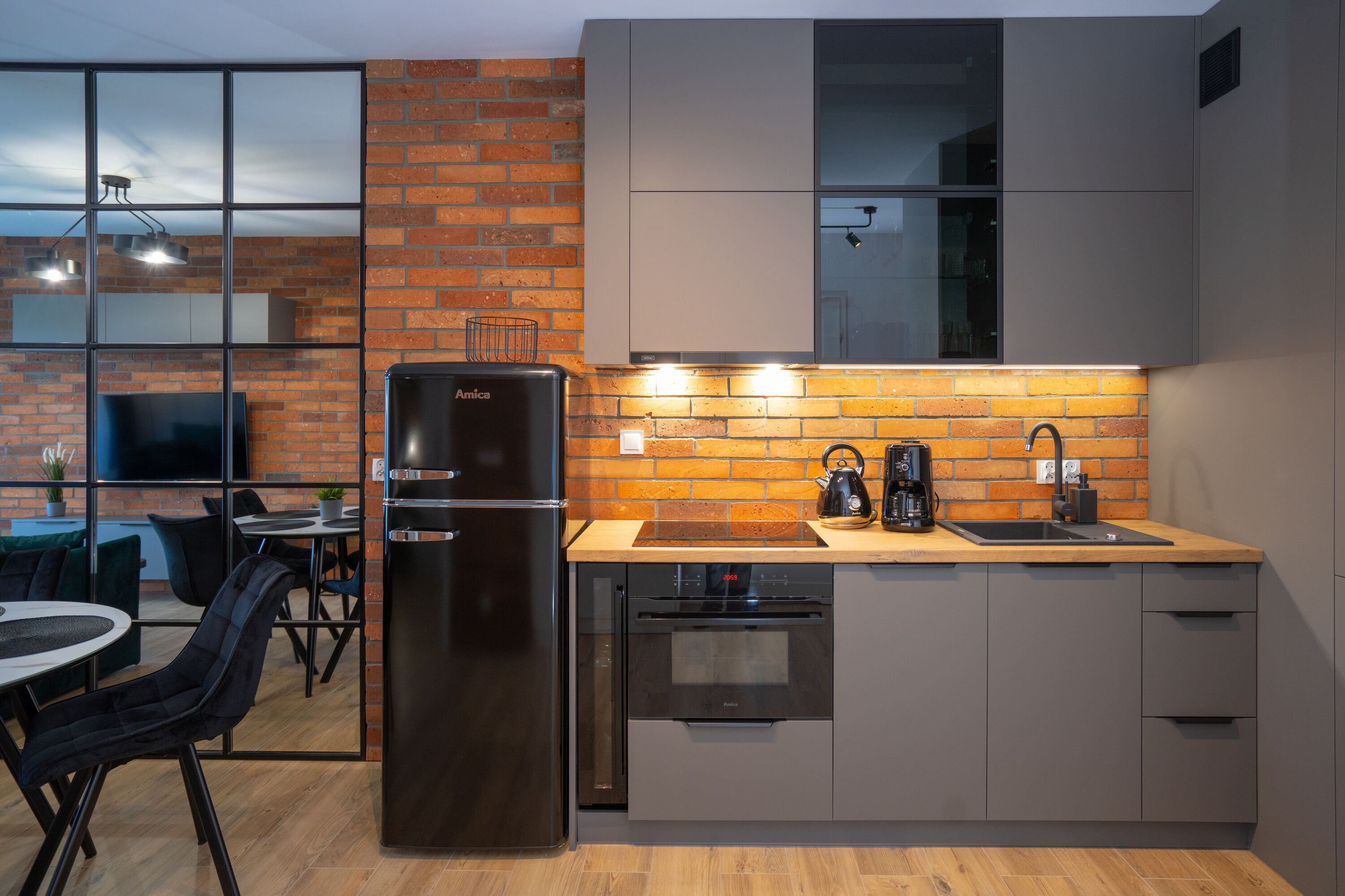 Una cucina moderna con una parete in mattoni, un frigorifero, una macchina del caffè e un lavello.