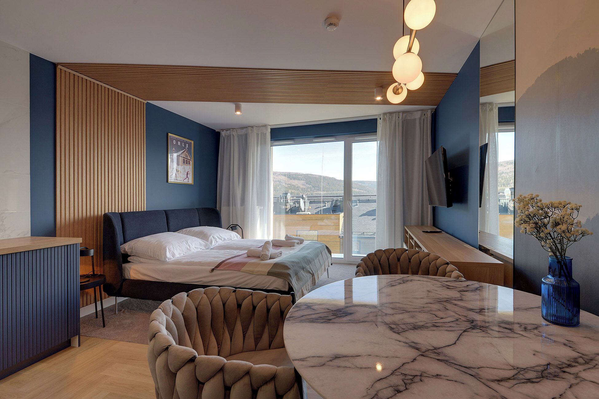 Een moderne hotelkamer met een bed, een eettafel en een televisie.