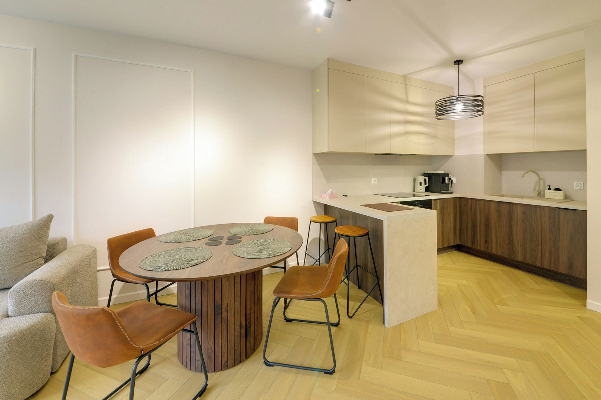 A compact kitchen with a central island, bar stools, and a dining table with placemats.