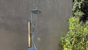 A wooden deck with a built-in showerhead, surrounded by greenery and a stone wall. - House (Calcatoggio)