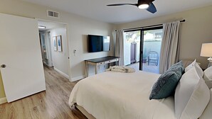 Habitación de hotel con una cama, un escritorio, un televisor y un ventanal corredizo al exterior.