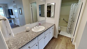 A bathroom with a granite countertop, white sink, and a shower with a floral curtain. - Brand NEW Remodel Single Level 2 Bd 2 Ba 2 Car Garage POOL UTC La Jolla Close to UCSD! (San Diego)