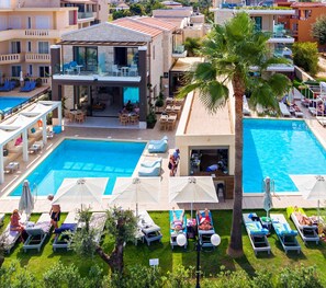 A hotel with a large pool area, outdoor seating, and a bar/lounge area. - Airis Boutique & Suites (Chania)