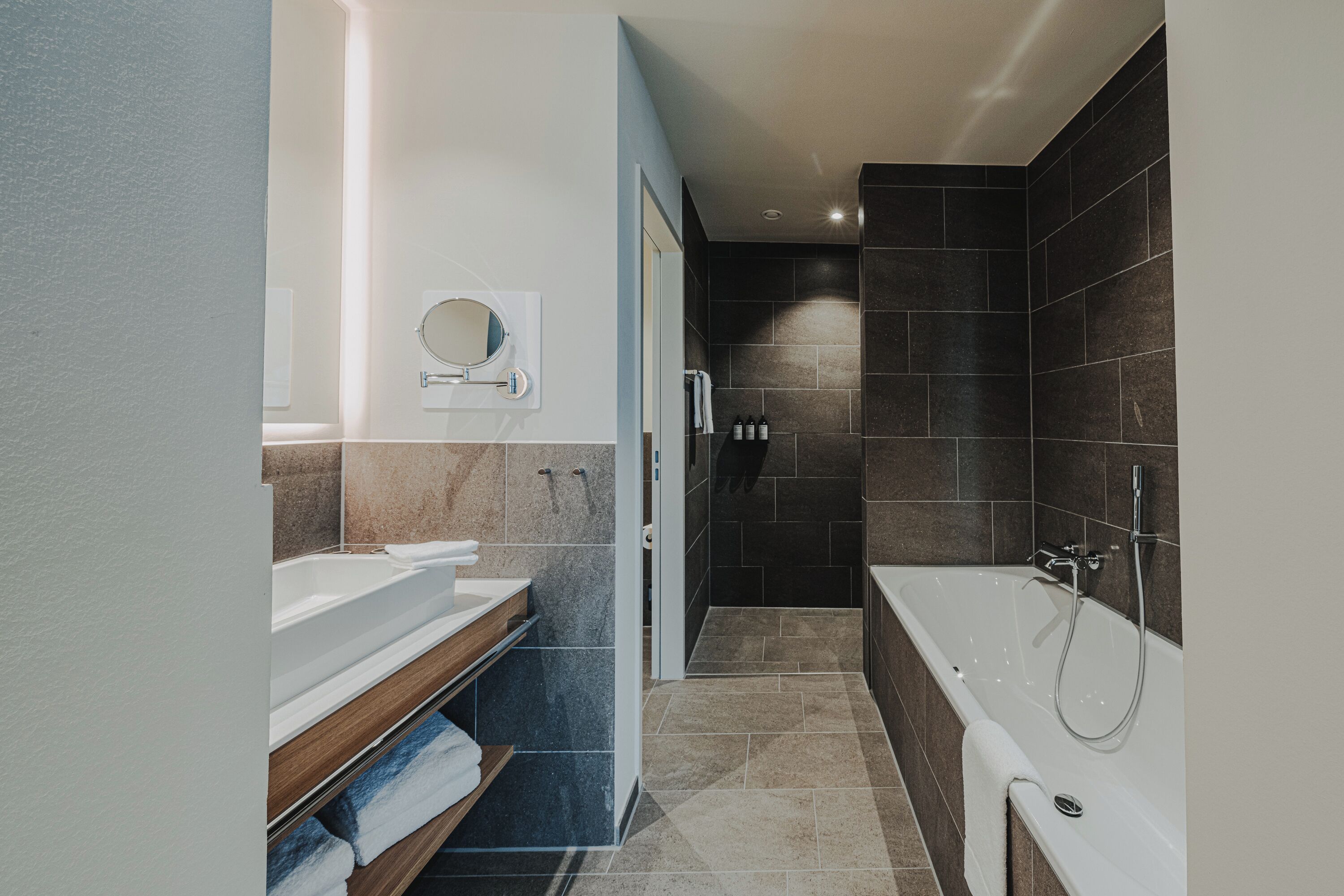 A modern bathroom with a bathtub, a vanity with a mirror, and a shower area.