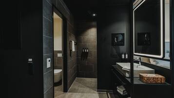 Een moderne badkamer met een donker thema, met een toilet, wastafel en een grote spiegel.