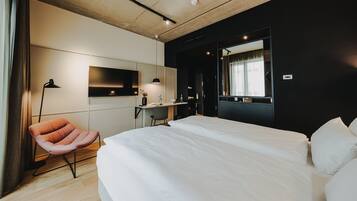A modern hotel room with a large bed, a desk with a chair, a flat-screen TV, and a large mirror.