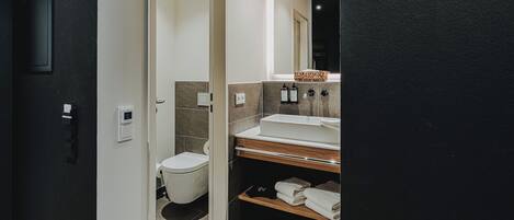 Une salle de bain moderne équipée de toilettes, d’un lavabo et d’un espace pour ranger les serviettes.