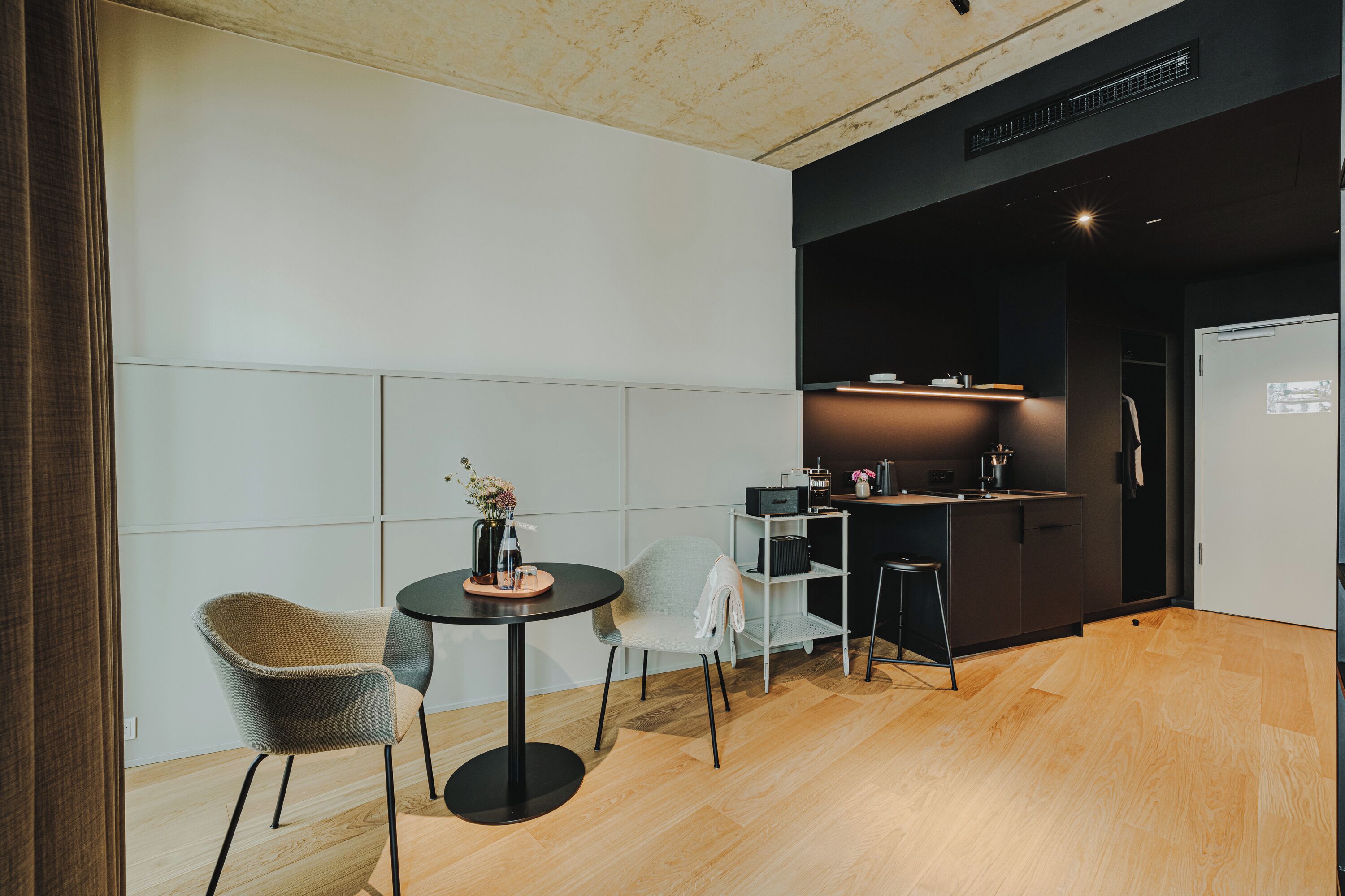 A modern kitchen with a black countertop, a small round table, and two chairs.