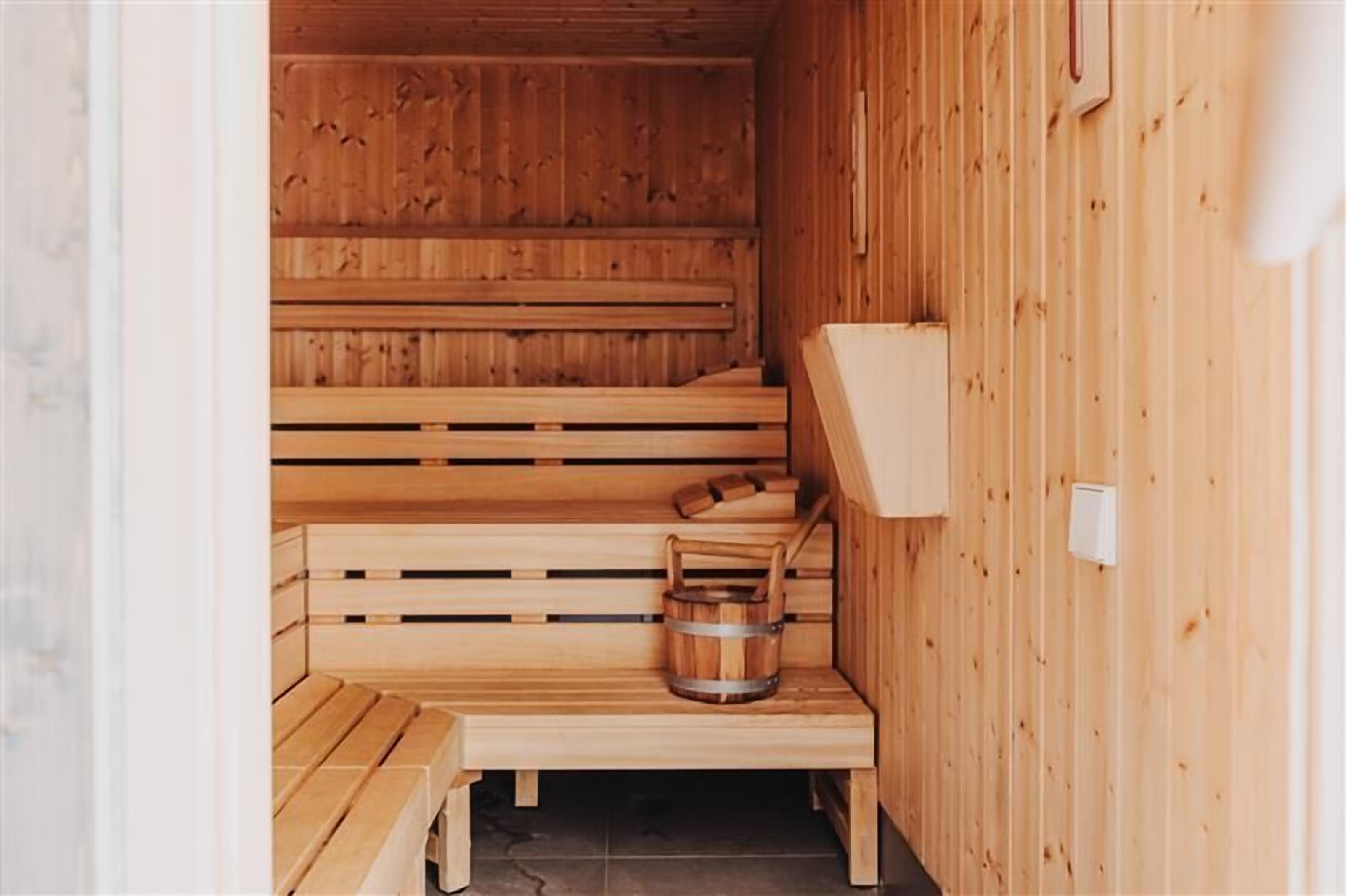 A wooden sauna with benches and a bucket.