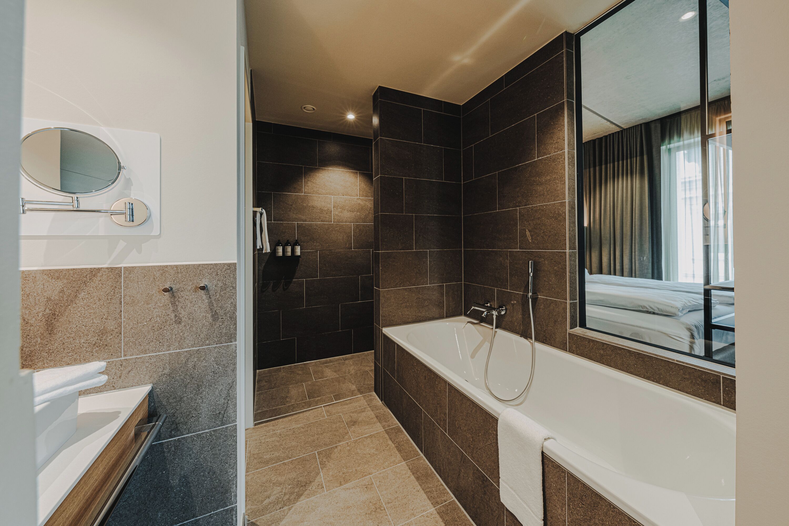 Un baño moderno con bañera, zona de ducha y un espejo grande.