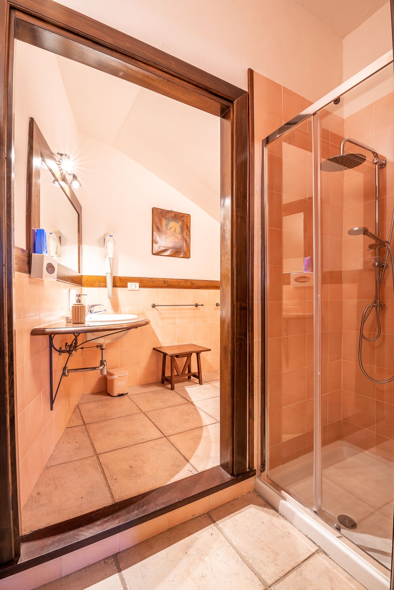 Un baño con cabina de ducha de vidrio, un lavamanos con espejo y un perchero para toallas.