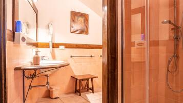 Un baño con cabina de ducha de vidrio, un lavamanos con espejo y un perchero para toallas.