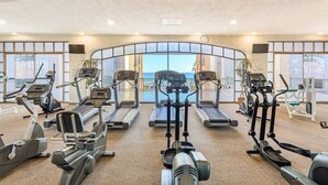 A gym with treadmills, ellipticals, and weight machines, overlooking a scenic view.
