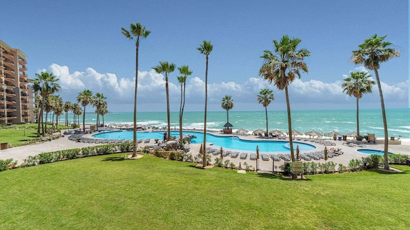 Un complexe hôtelier doté d’une piscine, de palmiers et offrant une vue sur l’océan.