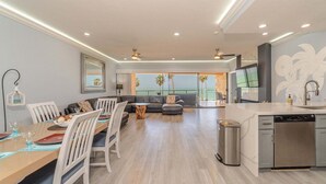 A modern living room with a dining area, a kitchen with a dishwasher, and a balcony with a view.