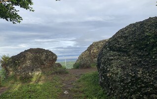 Paisagem rochosa com grandes pedras e uma ponte ao longe.