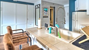 A modern kitchen with a large island, white cabinets, and a blue accent wall. - Chic Winter Park Studio w/ Community Hot Tub (Winter Park)