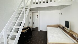 Ein Schlafzimmer mit Etagenbett, Schreibtisch mit Computer, Fernseher und einer Treppe.
