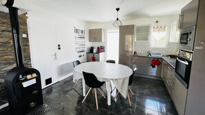 Eine moderne Küche mit Essbereich, ausgestattet mit Herd, Backofen, Mikrowelle und einer Wanduhr.