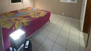 A bedroom with a bed, a desk, a chair, a window, and a door. - LA Maison DES Fées (Les Trois-Îlets)