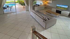 A spacious living area with a sofa, TV, and dining setup. - LA Maison DES Fées (Les Trois-Îlets)