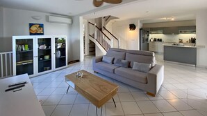 A modern living room with a sofa, coffee table, and a ceiling fan. - LA Maison DES Fées (Les Trois-Îlets)